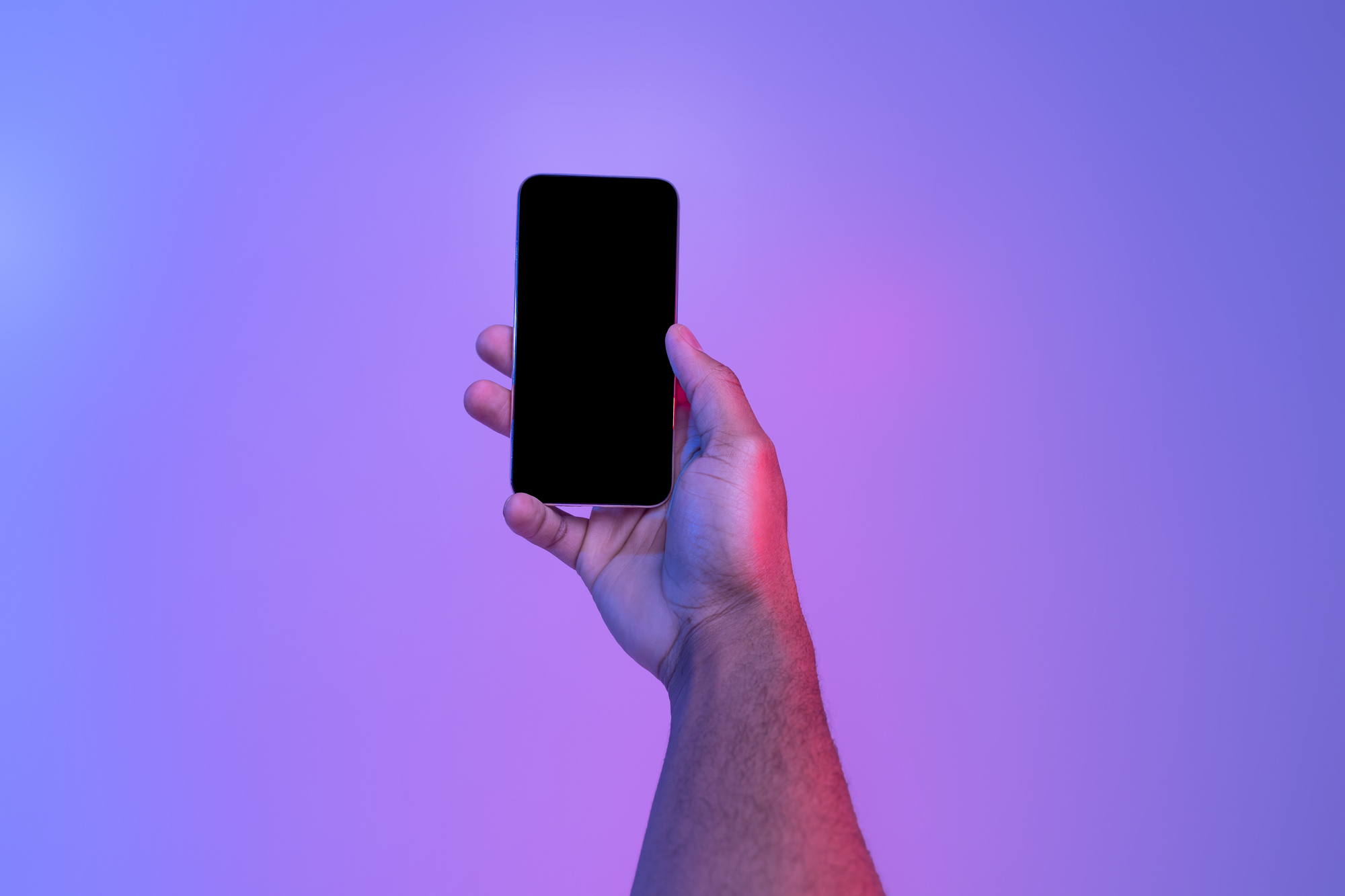Mobile technologies. Black male hand holding cellphone with blank screen over purple neon background, african american man demonstating copy space for app design, close up, mockup image