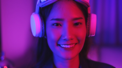 Young asian woman is using virtual reality headset. Neon light studio portrait. Concept of virtual reality, simulation, gaming and future technology.Asian woman play game in bedroom.